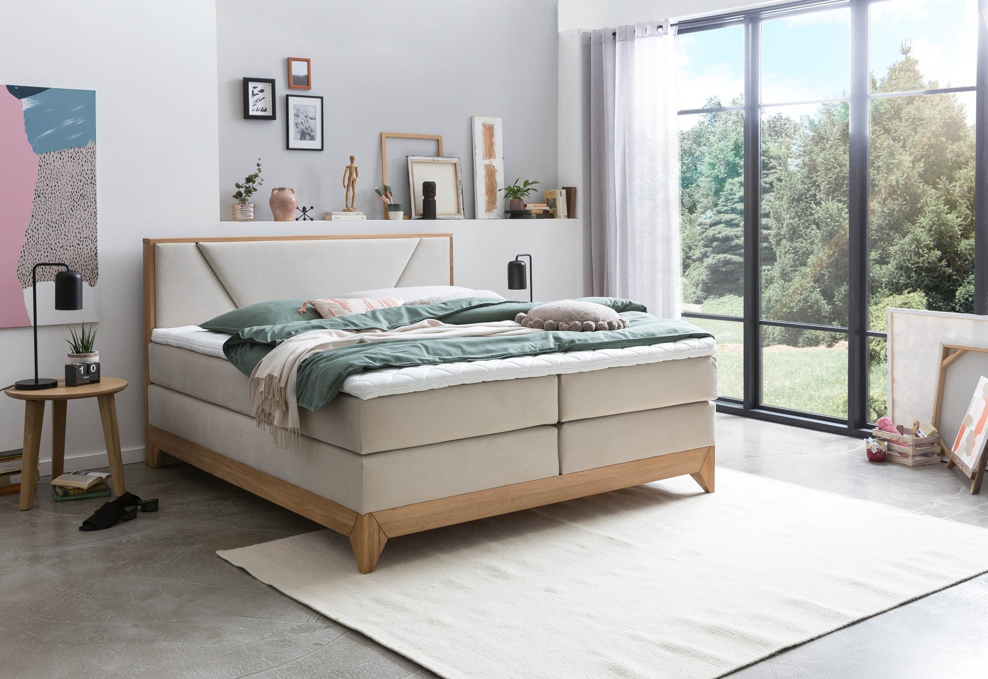 Helles Boxspringbett mit cremefarbenem Stoffbezug und Holzfüßen in modernem Schlafzimmer